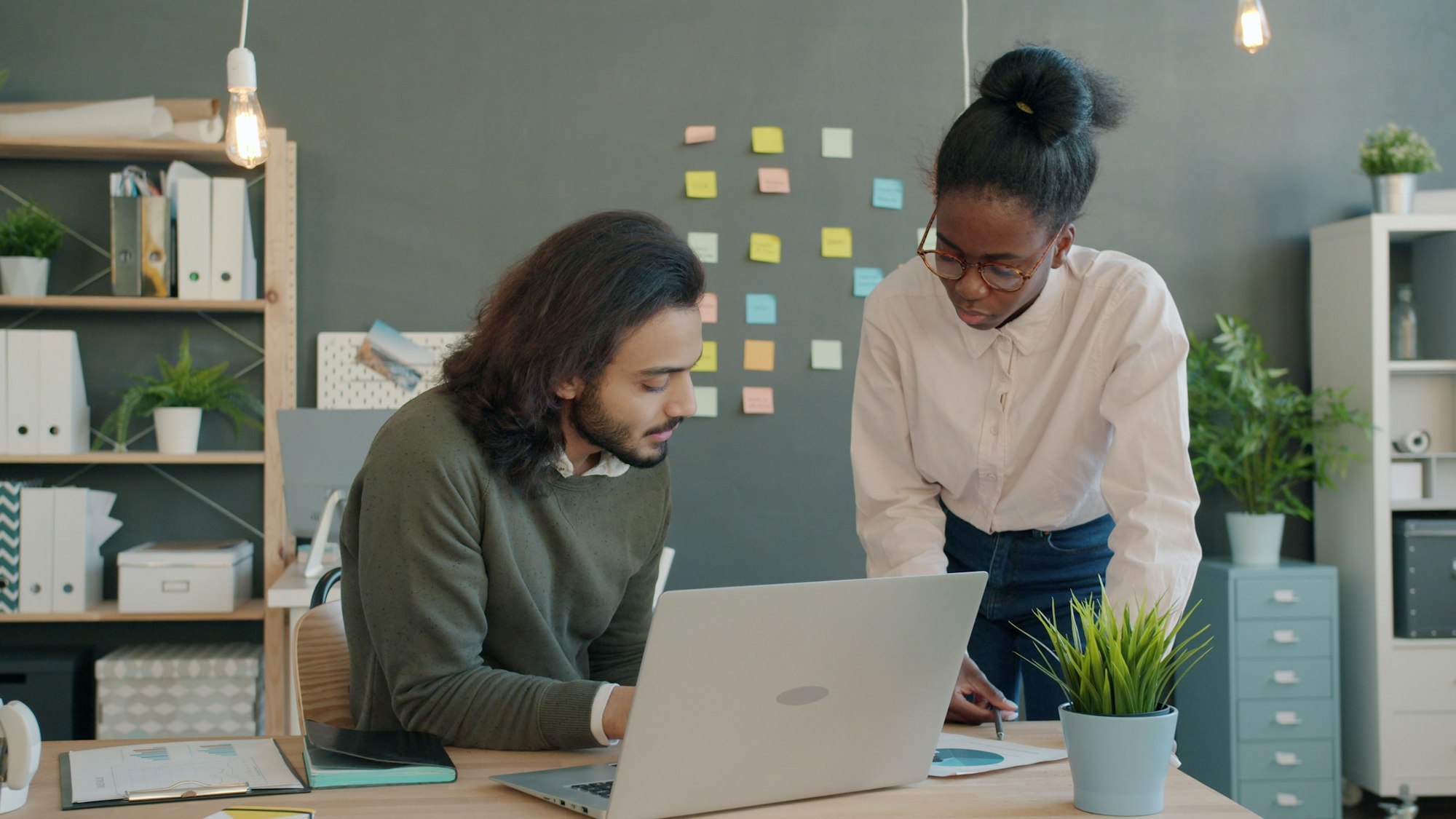 Two colleagues at a desk, working through a plan together on one screen